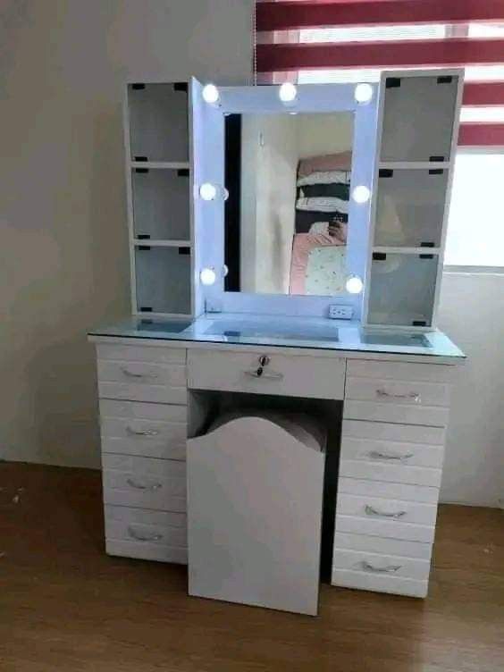 White Vanity Table with Lights and Stool (Category: Tables & Sets) located in Mabalacat. Submitted by joemamangun01 (Listing ID 1437597421, Image 3). Description: - White vanity table with built-in lights - Includes matching white stool - Multiple drawers and side shelves for storage - Sleek design with gold-colored handles - Ideal for makeup and skincare routines - Provides ample space for beauty essentials.