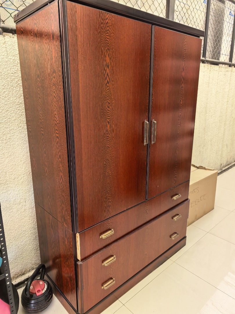 Wooden Wardrobe with Drawers (Category: Shelves, Cabinets & Racks) located in Las Pinas. Submitted by teampeewee888 (Listing ID 1437660118, Image 1). Description: - Wooden wardrobe with two doors and two drawers - Features multiple shelves and storage compartments - Dark wood finish - Gold-colored handles - Well-maintained condition - Ample storage space for clothes and other items.