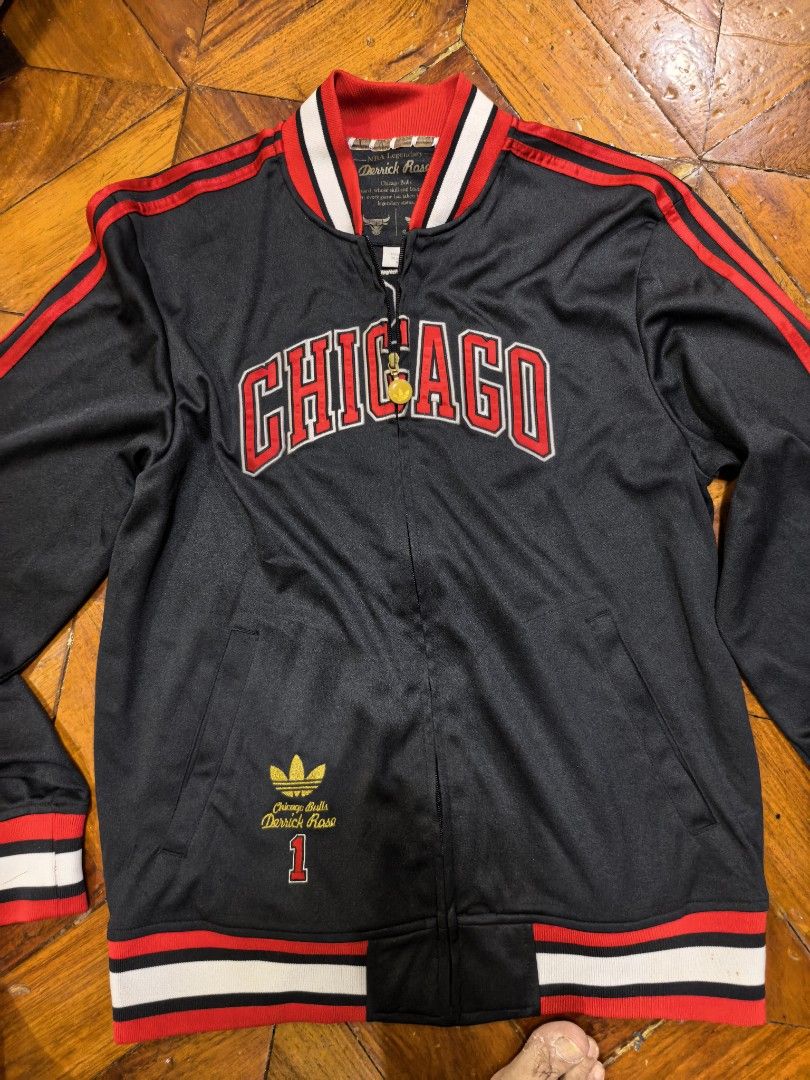 Adidas Derrick Rose Chicago Bulls Jacket (Category: Coats, Jackets and Outerwear) located in Manila. Submitted by snooks1938 (Listing ID 1437791912, Image 2). Description: For Grab!! NBA ADIDAS DERECK ROSE VARSITY JACKET BULLS. Size Medium.. 100% Authentic or money back.. - Adidas Chicago Bulls Derrick Rose jacket - Black base with red and white accents - Features "ROSE" on the back - Adidas and NBA logos - Zip-up style with collar Pm for any Que