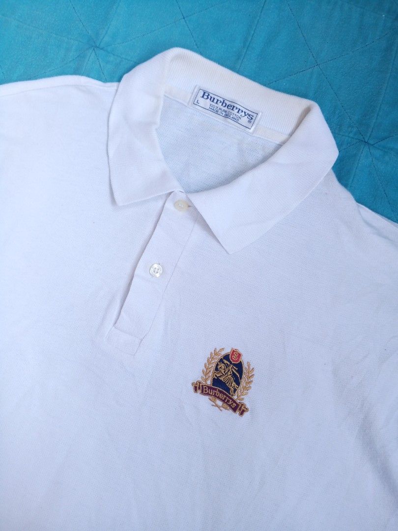 Burberrys White Polo Shirt (Category: Tshirts & Polo Shirts ) located in Las Pinas. Submitted by allhandpick (Listing ID 1437854332, Image 2). Description: - Burberrys white polo shirt - Embroidered Burberrys logo - 100% cotton - Made in England - Collared neckline - Short sleeves - Button-up placket.