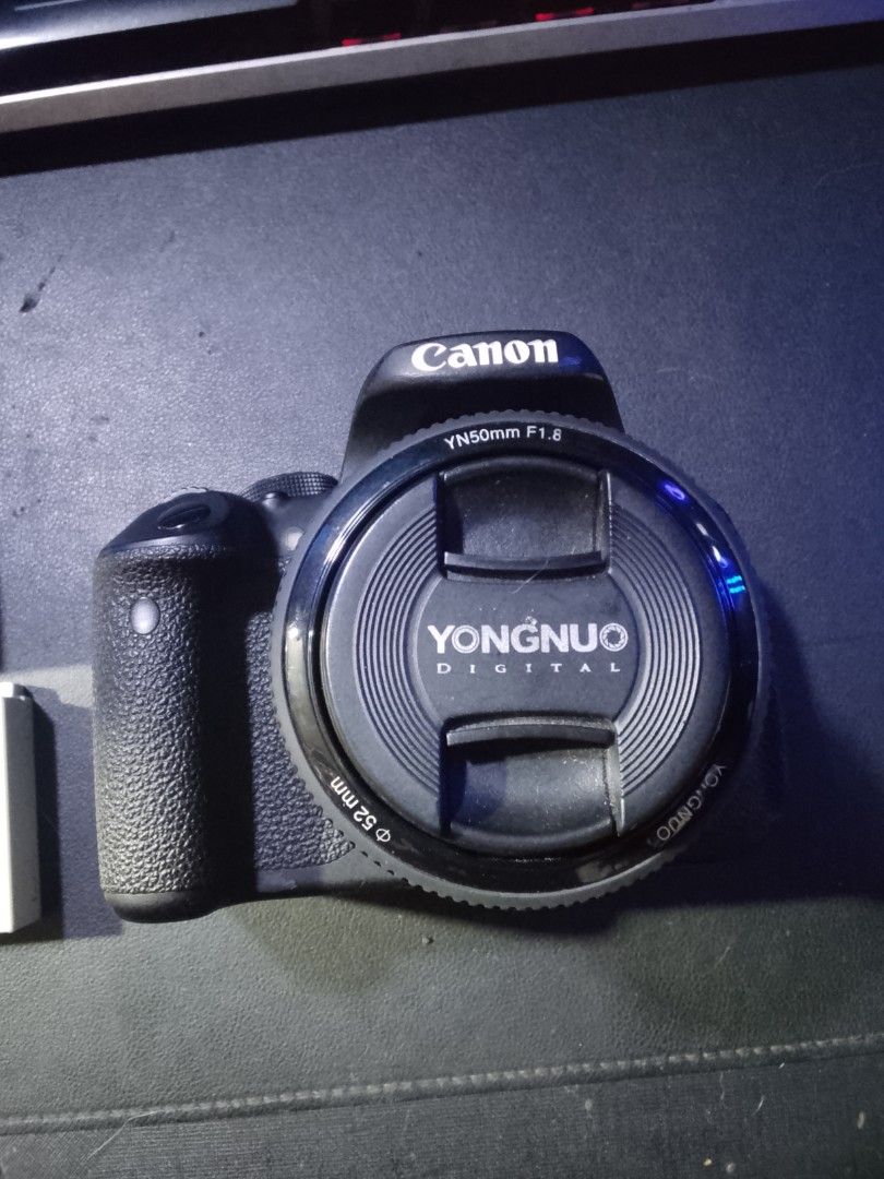 Canon EOS 700D with Yongnuo Lens (Category: Cameras) located in Manila. Submitted by asero578 (Listing ID 1437900687, Image 3). Description: - Canon EOS 700D camera - Yongnuo YN50mm F1.8 lens - Includes charger and two batteries - Lens cap included - Black camera body - 52mm filter thread on lens - Features mode dial and various buttons.
