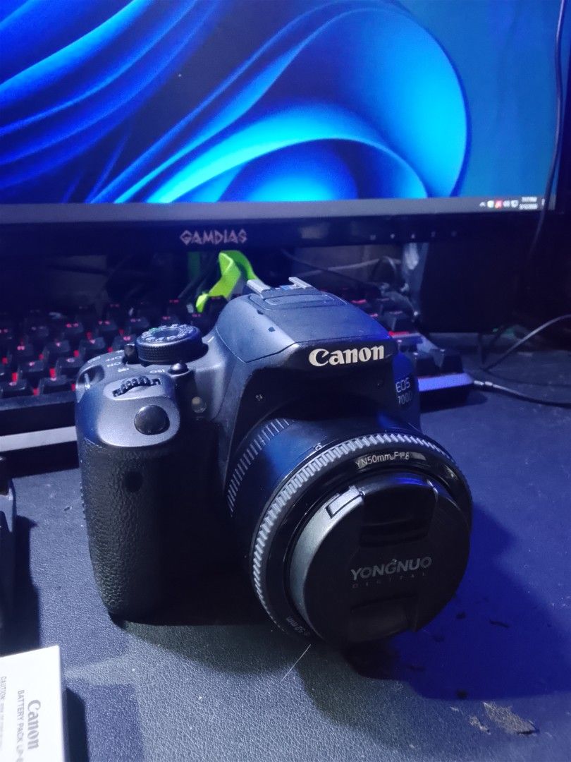 Canon EOS 700D with Yongnuo Lens (Category: Cameras) located in Manila. Submitted by asero578 (Listing ID 1437900687, Image 2). Description: - Canon EOS 700D camera - Yongnuo YN50mm F1.8 lens - Includes charger and two batteries - Lens cap included - Black camera body - 52mm filter thread on lens - Features mode dial and various buttons.
