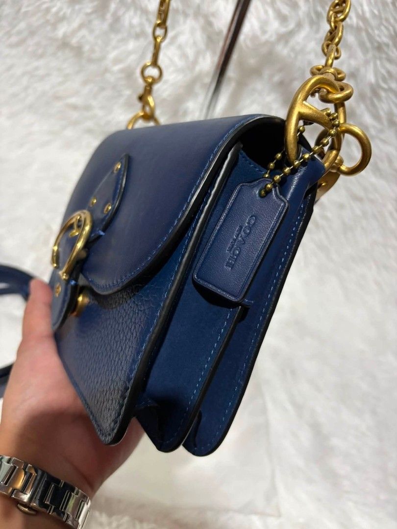 Coach Beat Shoulder Bag 18 (Category: Luxury Bags & Wallets) located in Malabon City. Submitted by cbpreloveditems (Listing ID 1437931340, Image 2). Description: - Coach Beat Shoulder Bag 18 - Navy blue leather exterior - Gold-tone hardware - Detachable crossbody strap - Top handle with chain detail - Flap closure with buckle - Zippered interior pocket - Includes dust bag - Comes with tag.