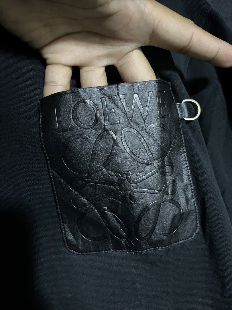 Loewe Black Pocket T-shirt (Category: Tshirts & Polo Shirts ) located in Panabo. Submitted by edition_25 (Listing ID 1437883828, Image 2). Description: Black Loewe T-shirt with a leather pocket. Features the Loewe logo embossed on the pocket. Made in Portugal. Size S. The shirt has a crew neck and short sleeves. The tag is visible, showing the brand and size. - 21 width - 26.5 length - Excellent condition - 9.8/10 color rate.