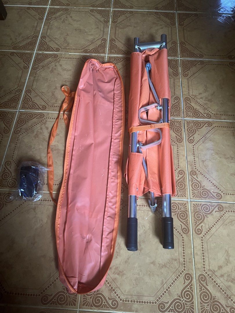 Orange Folding Stretcher with Carrying Bag (Category: Other Assistive Aids) located in Las Pinas. Submitted by jerri44 (Listing ID 1437789536, Image 2). Description: - Orange folding stretcher with matching carrying bag. - Features a sturdy metal frame and handles. - Constructed from durable, water-resistant material. - Folds compactly for storage and portability. - Perfect for emergency situations and medical use..