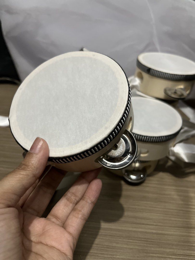 Small Tambourines (Category: Musical Instruments) located in Quezon City. Submitted by raca_preloved (Listing ID 1437845173, Image 1). Description: Used once 9pcs 4in - Small, round tambourines - White drumhead - Light-colored wooden frame with black trim - Silver jingles - White ribbon attached - New and unused - Great for musical activities or party favors.