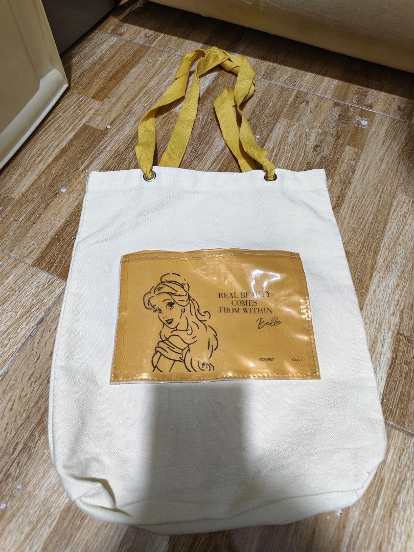 Disney Belle Tote Bag (Category: Tote Bags) located in Makati City. Submitted by abegailbrezuela (Listing ID 1437983220, Image 1). Description: - Disney's Beauty and the Beast themed tote bag. - Features Belle design. - White canvas body. - Yellow handles and pocket. - Pocket features Belle's image and the quote "Real Beauty Comes From Within." - Made of durable canvas material. - Ideal for carrying various items..