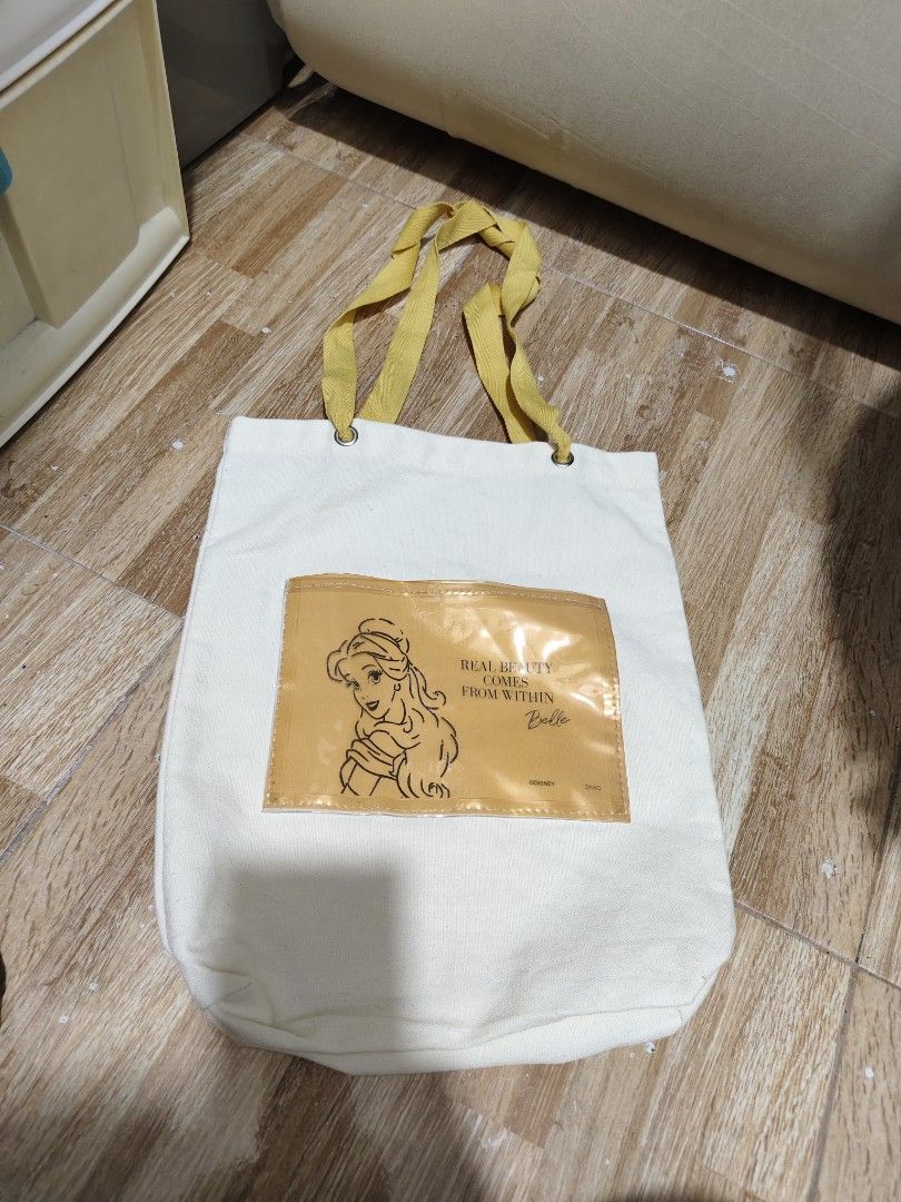 Disney Belle Tote Bag (Category: Tote Bags) located in Makati City. Submitted by abegailbrezuela (Listing ID 1437983220, Image 2). Description: - Disney's Beauty and the Beast themed tote bag. - Features Belle design. - White canvas body. - Yellow handles and pocket. - Pocket features Belle's image and the quote "Real Beauty Comes From Within." - Made of durable canvas material. - Ideal for carrying various items..