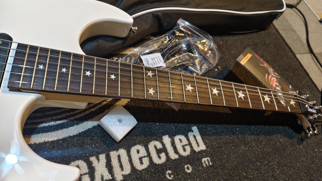 Electric Guitar with Star Inlays (Category: Musical Instruments) located in Pasig City. Submitted by tupriomichaeljohn (Listing ID 1438016129, Image 2). Description: - White electric guitar - Star inlays on fretboard - Features a tremolo system - Includes a black Fender gig bag - Comes with a set of new tuning pegs - Still wrapped in plastic.