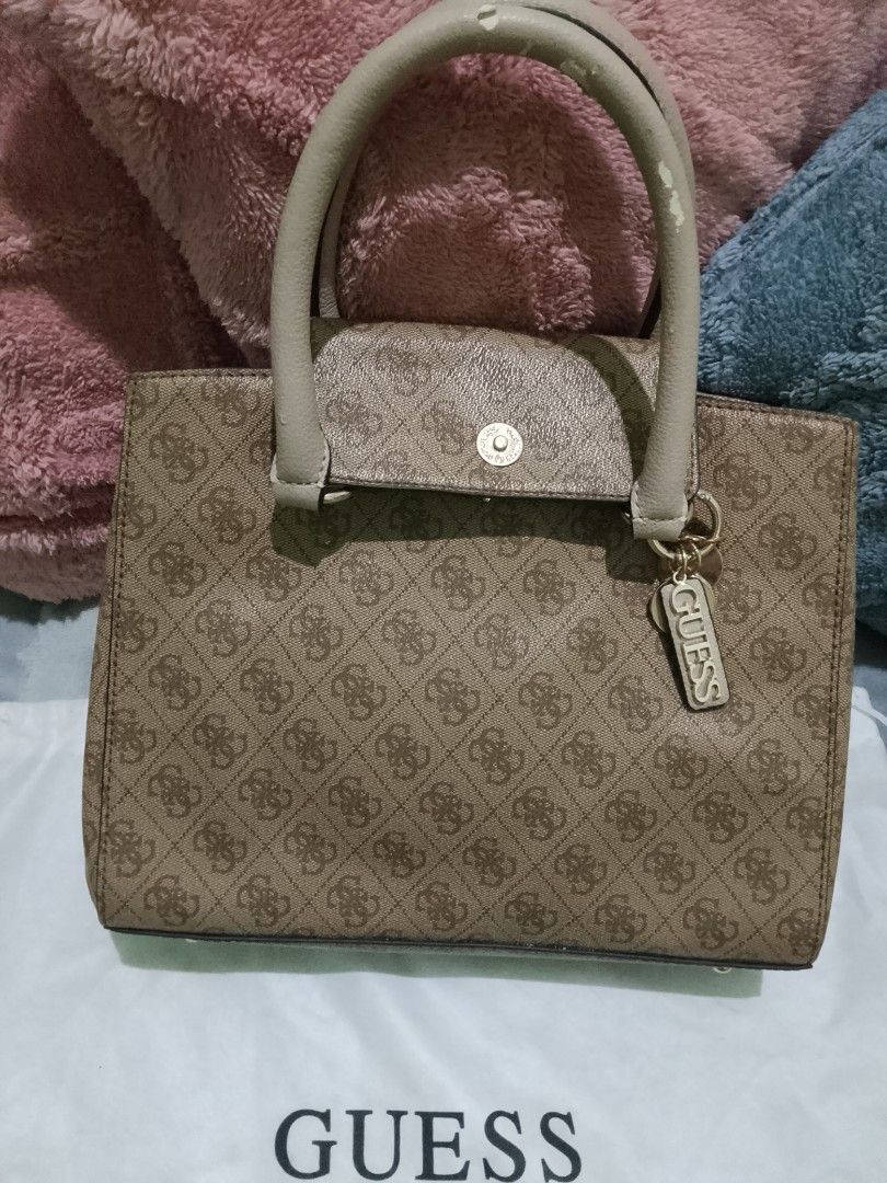 Guess Handbag (Category: Shoulder Bags) located in Bulacan. Submitted by emscoolstuff (Listing ID 1438108913, Image 2). Description: - Original and Authentic Guess handbag - Brown monogram pattern - Top handle design - Beige handles - Rectangular shape - Flap closure - Guess logo on front - Includes Guess tag - Includes dust bag Note: The handle has a small dent.