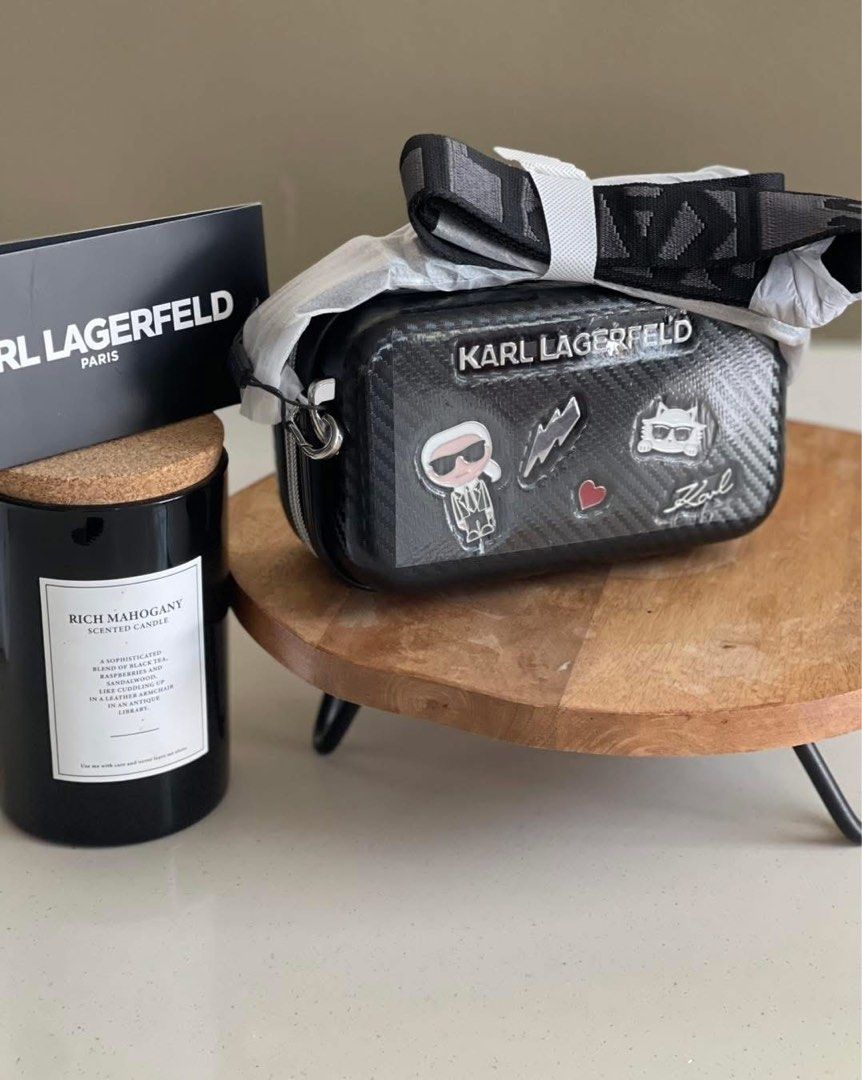 Karl Lagerfeld Crossbody Bag (Category: Cross-body Bags) located in Caloocan City. Submitted by Roowchelly (Listing ID 1438060935, Image 1). Description: - Karl Lagerfeld crossbody bag - Carbon fiber-like texture - Multiple patches - Detachable strap with Karl Lagerfeld logo - Zipper closure - Silver-tone hardware - Includes original box - Displayed on a wooden stand.