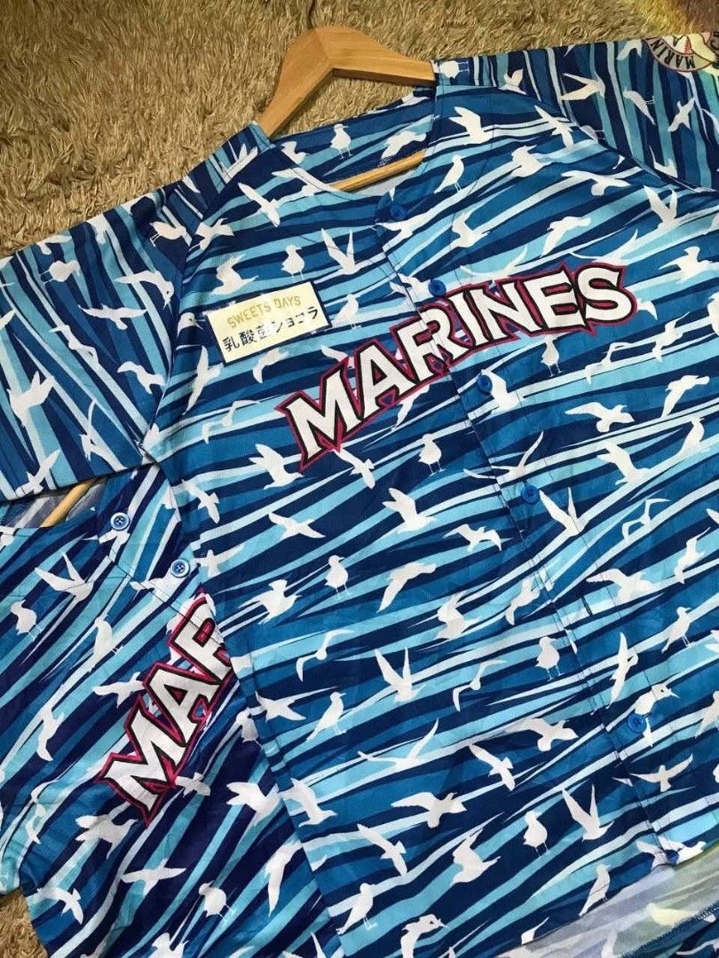 Marines Baseball Jersey (Category: Tshirts & Polo Shirts ) located in Navotas City. Submitted by jericafits (Listing ID 1438051759, Image 3). Description: - [ ] Marines Size:L Dimes:22.5 x 27.5-29.5 ₱ 300(2pcs Available) - Japanese baseball jersey - Blue and white bird pattern - "MARINES" text on front - Button-up design - Short sleeves.