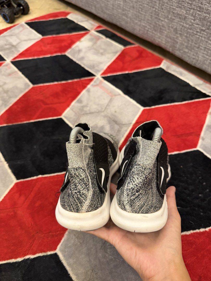 Nike Free RN Flyknit 2018 Sneakers (Category: Sneakers) located in San Jose. Submitted by affordabletrendsby_cai (Listing ID 1438034213, Image 3). Description: Nike Free RN Flyknit 2018 sneakers. Features a gray and black Flyknit upper with a black strap and white sole. The Nike swoosh logo is visible on the side. The sole is white with "NIKE FREE" printed on the side. The shoes have a sock-like fit..