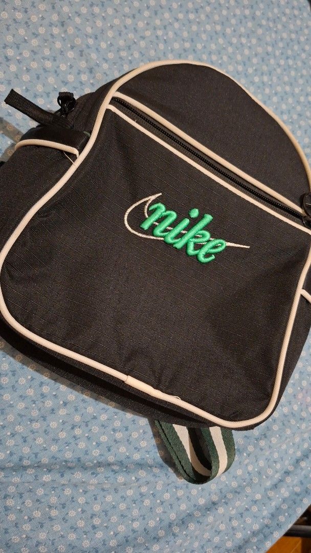 Nike Mini Backpack Black (Category: Backpacks) located in Pasig City. Submitted by kkdvm (Listing ID 1438080870, Image 1). Description: - Nike mini backpack - Black exterior with white trim - Green and white striped strap - Nike logo on front - Zipper closure - Compact size - Ideal for small items - Minor imperfection on strap.