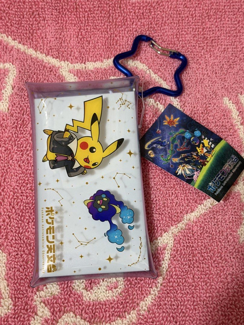 Pokemon Astronomical Observatory Card Holder (Category: Wallets & Card Holders) located in Bacoor. Submitted by vikkavi (Listing ID 1438083631, Image 1). Description: - Pikachu card holder with a cosmic design. - Features a star-shaped carabiner. - Comes with a tag featuring Japanese text and Pokemon characters. - Presented in a clear plastic case with snap closures. - Design includes constellations and "Pokemon Astronomical Observatory" text..