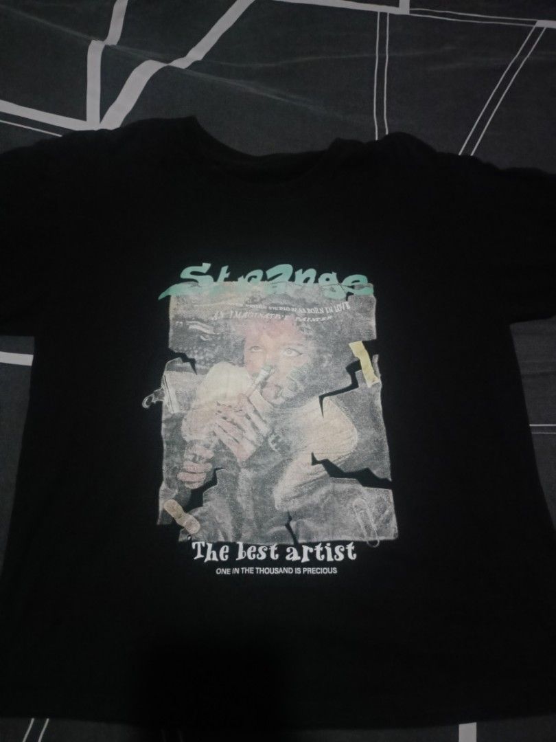 Strange The Lost Artist Graphic Tee (Category: Tshirts & Polo Shirts ) located in Manila. Submitted by around_marikina (Listing ID 1438099165, Image 1). Description: - Black graphic tee - Front print: Person with "Strange" and "The lost artist" - Back print: "Strange" - Short sleeves - Crew neck.