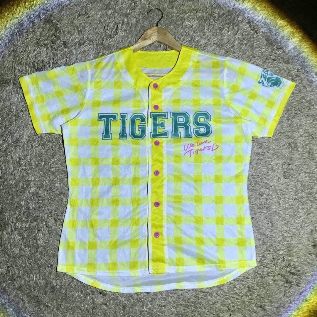 Tigers Baseball Jersey (Category: Tshirts & Polo Shirts ) located in Navotas City. Submitted by jericafits (Listing ID 1438052126, Image 1). Description: - [ ] Tigers Pattern Size: L Dimes: 21 x 26 ₱300 - Yellow and white checkered design - "TIGERS" printed on the front - Button-up style with pink buttons - "We love Tigers" text on the front - Small logo on the sleeve - Short sleeves - Yellow collar.