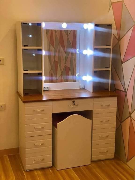 Vanity Table with Lights and Stool (Category: Tables & Sets) located in Mabalacat. Submitted by joemamangun01 (Listing ID 1437989024, Image 2). Description: - Vanity table with built-in mirror and lights - Multiple drawers and side cabinets for storage - Includes matching stool with cushioned seat - Wooden table top - White frame - Ideal for bedroom or dressing area.