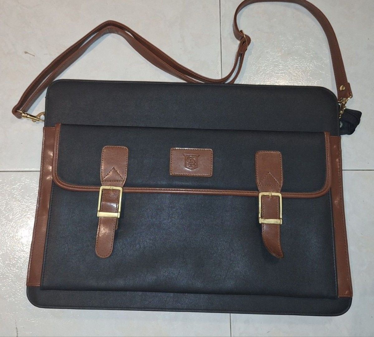 Classic Brown Briefcase (Category: Briefcases) located in Singapore. Submitted by hk267066 (Listing ID 1437726335, Image 1). Description: Vintage black, brown briefcase with shoulder strap and two untarnished gold buckle closures. Excellent condition. Size: 43cm Length by 33 cm Breadth. Perfect for carrying documents or a laptop. Self-collection. New one may cost about $500..