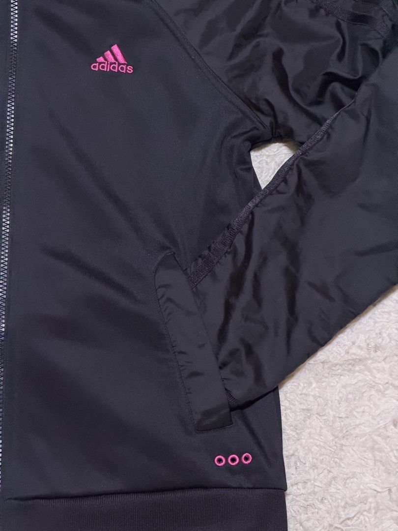 Adidas Black Track Jacket (Category: Coats, Jackets and Outerwear) located in San Fernando. Submitted by aircatz (Listing ID 1438121237, Image 3). Description: - Black Adidas track jacket - Pink Adidas logo on chest - Pink details at the bottom - Full zip closure - Side pockets - High collar - Classic three stripes on sleeves.