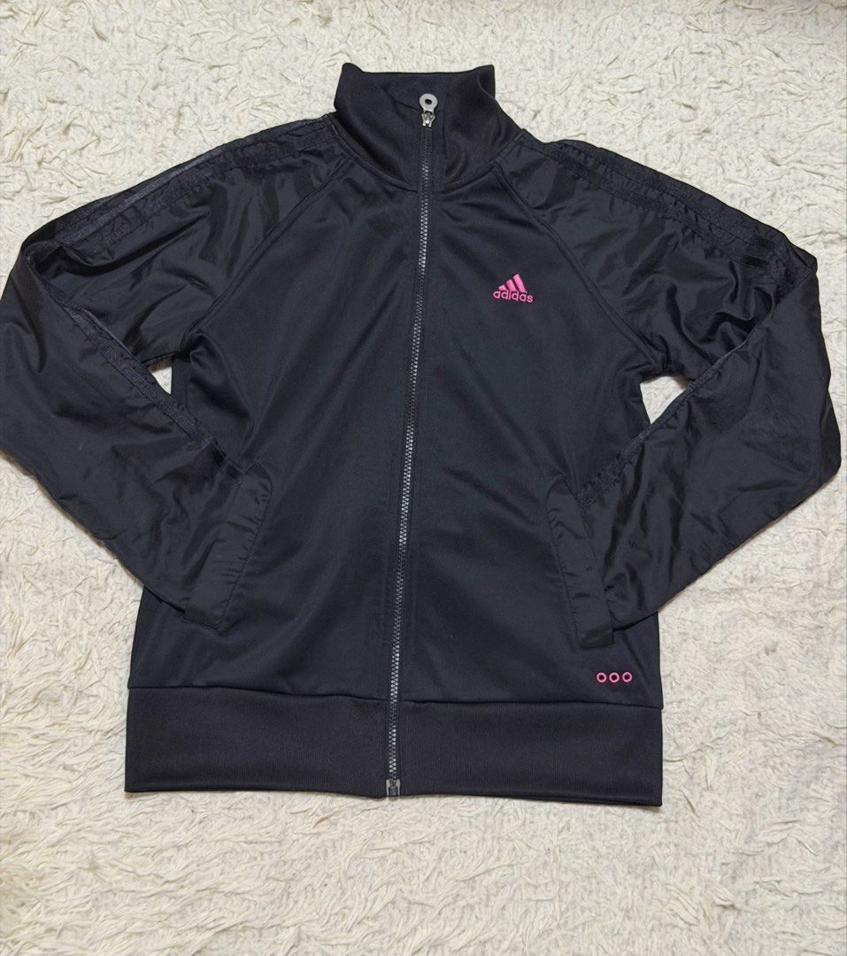 Adidas Black Track Jacket (Category: Coats, Jackets and Outerwear) located in San Fernando. Submitted by aircatz (Listing ID 1438121237, Image 1). Description: - Black Adidas track jacket - Pink Adidas logo on chest - Pink details at the bottom - Full zip closure - Side pockets - High collar - Classic three stripes on sleeves.