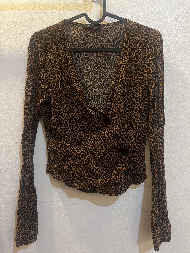 Bershka Leopard Print Blouse (Category: Blouses) located in Mandaluyong City. Submitted by declutterrie (Listing ID 1438154185, Image 2). Description: - Bershka blouse - Leopard print design - Size: S - Wrap-style front with button closures.