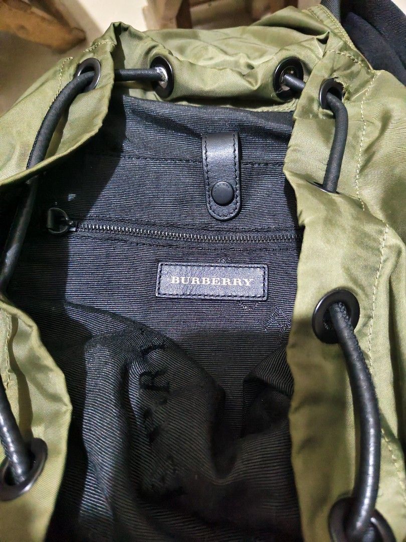 Burberry Nylon Rucksack Backpack (Category: Luxury Bags & Wallets) located in Munoz. Submitted by harm0nica337 (Listing ID 1438251778, Image 3). Description: - Olive green backpack with black accents - Drawstring closure and top handle Thrifted item : self authenticated only Flaws: tear on inner lining, tear on one side of compartment, peeling and other issues as shown in the last pics mop: gcash (price +SF) j&t express.