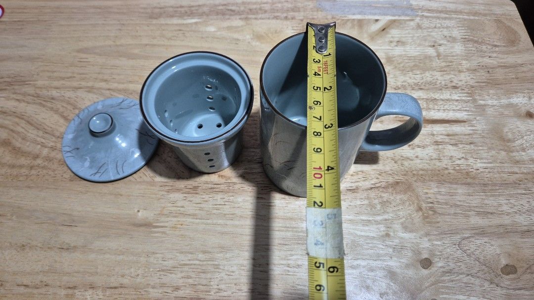 Ceramic Tea Cup with Infuser (Category: Coffee & Tea Tableware) located in Makati City. Submitted by caesteban (Listing ID 1438264541, Image 2). Description: - Ceramic teacup set - Includes cup, lid, and infuser - Cup color: Greyish-blue - Features a floral design - Infuser for steeping tea leaves.