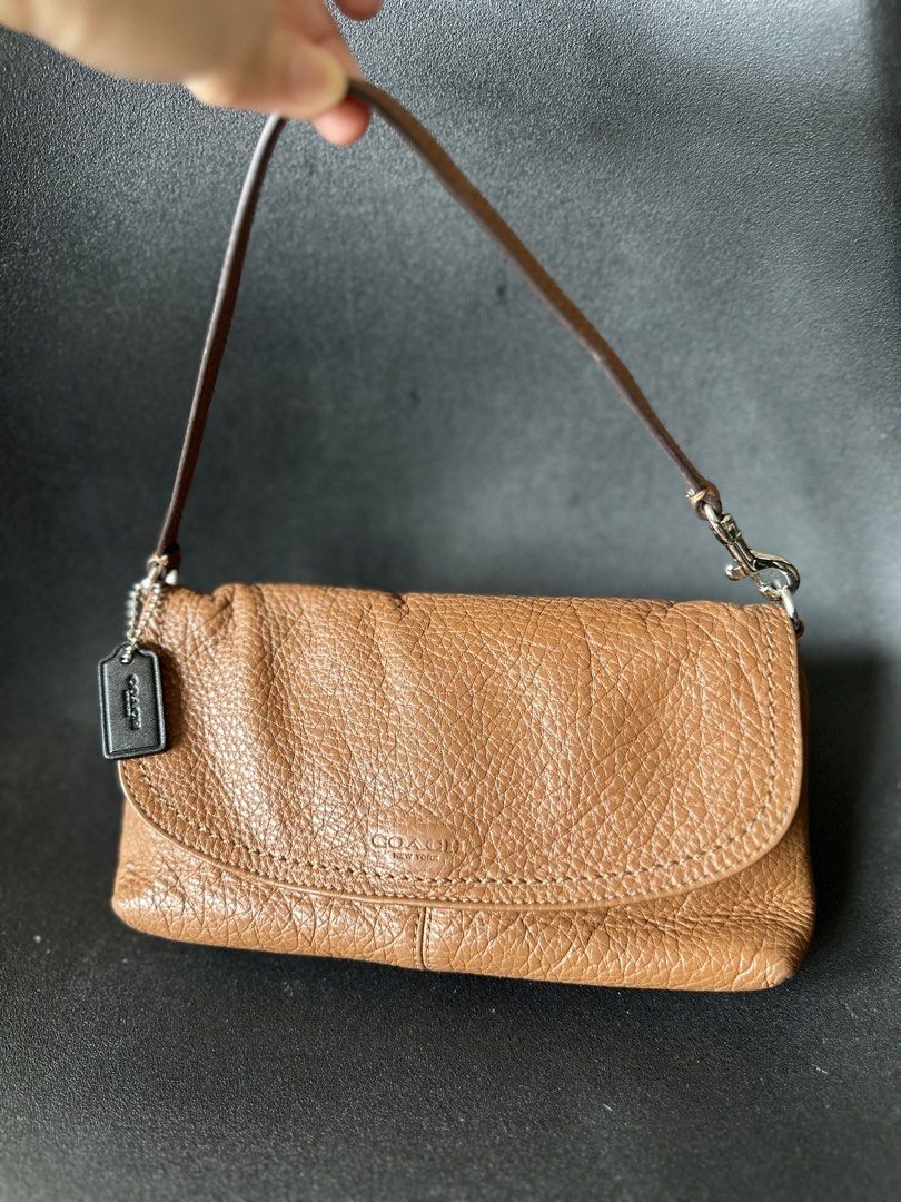Coach Brown Leather Wristlet Handbag (Category: Luxury Bags & Wallets) located in Makati City. Submitted by Bulats (Listing ID 1438124603, Image 1). Description: With back slip pocket that fits iphone14 pro max. Small, what you see is what you get- w/ punit but can be glued easily. Parang wallet in chain/strap ang capacity. - Original Coach wristlet - Brown leather - Top flap closure - Wrist strap included - Features Coach hangtag - Interior with