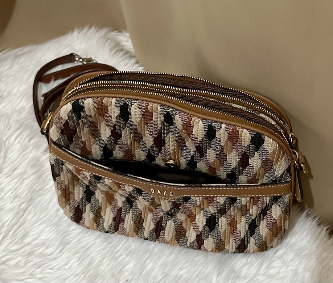DAKS Crossbody Bag (Category: Cross-body Bags) located in Rizal. Submitted by stuffbuyph (Listing ID 1438124227, Image 1). Description: - DAKS crossbody bag - Unique patterned fabric exterior - Brown leather accents - Detachable shoulder strap - Multiple zippered compartments - Light-colored fabric lining.
