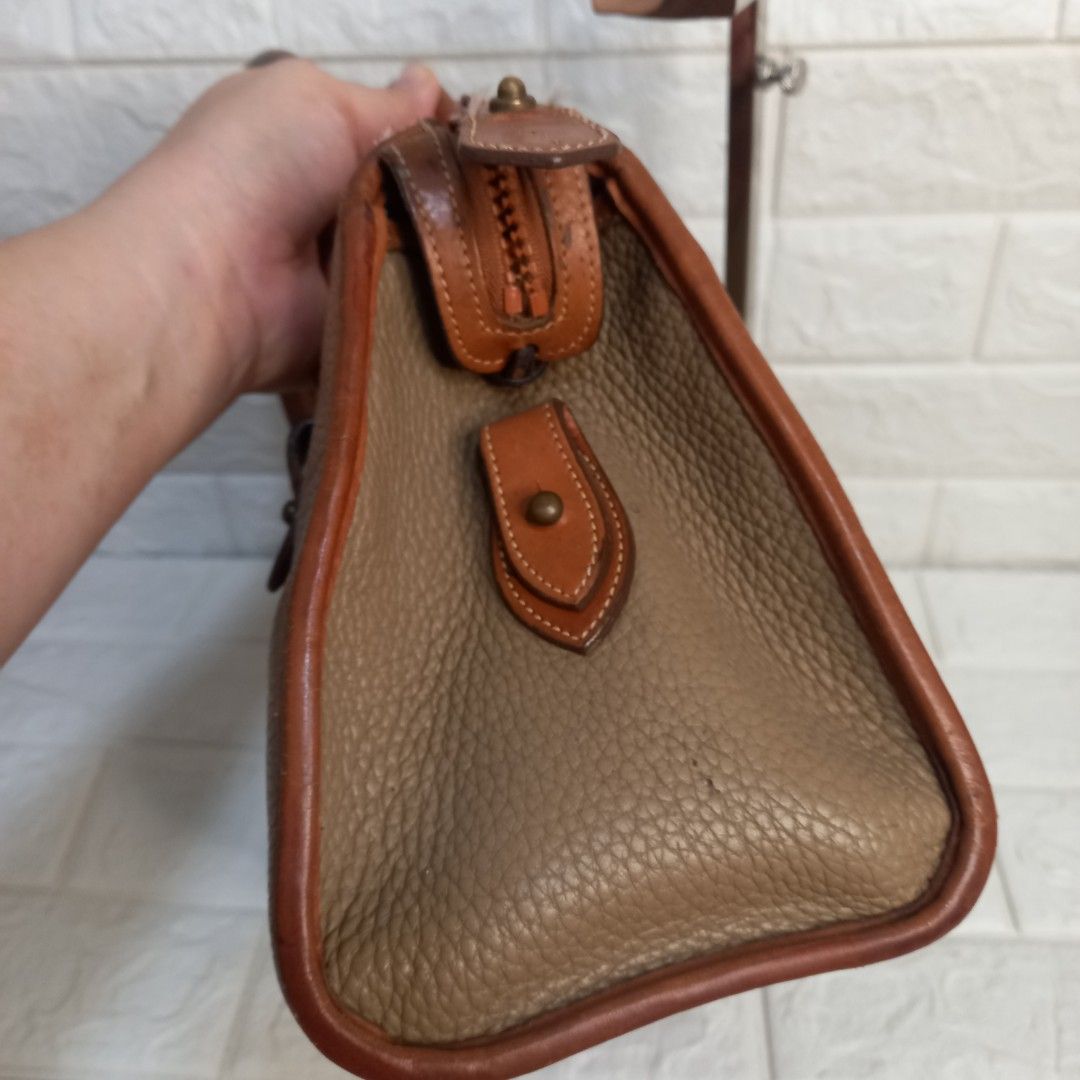 Dooney & Bourke Vintage Leather Handbag (Category: Tote Bags) located in Las Pinas. Submitted by etoksi1234 (Listing ID 1438248551, Image 3). Description: Pre-loved Dooney & Bourke Vintage leather handbag in brown and tan. Features a top handle, shoulder strap, zip closure, and logo. Includes metal hardware and feet..