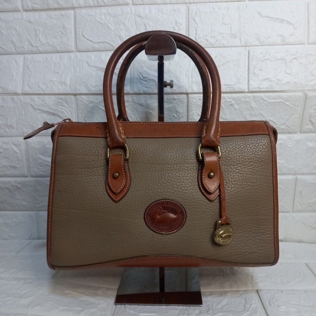 Dooney & Bourke Vintage Leather Handbag (Category: Tote Bags) located in Las Pinas. Submitted by etoksi1234 (Listing ID 1438248551, Image 1). Description: Pre-loved Dooney & Bourke Vintage leather handbag in brown and tan. Features a top handle, shoulder strap, zip closure, and logo. Includes metal hardware and feet..