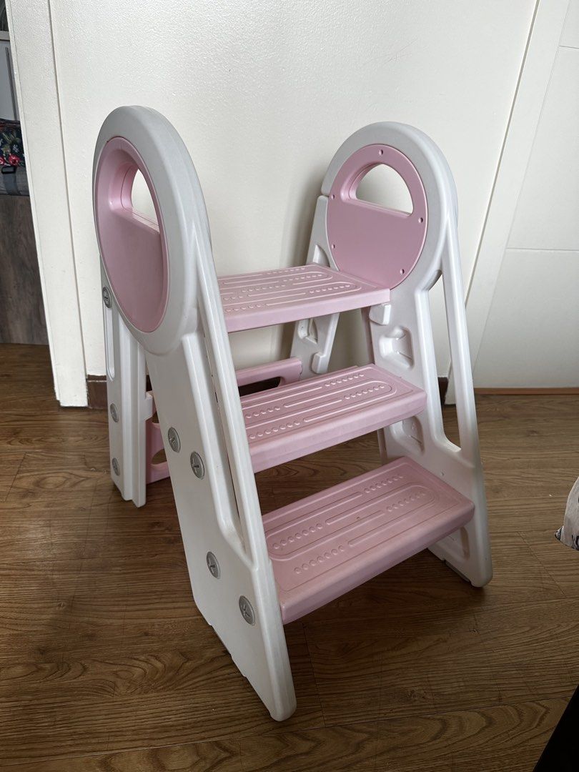 Foldable Step Stool with Handle (Category: Chairs) located in Manila. Submitted by mike.ed (Listing ID 1438123515, Image 1). Description: - Foldable step stool for kids - Three steps for easy access - Convenient carrying handle - Folds flat for compact storage - Durable white and pink plastic construction - Ideal for reaching high places or helping little ones.