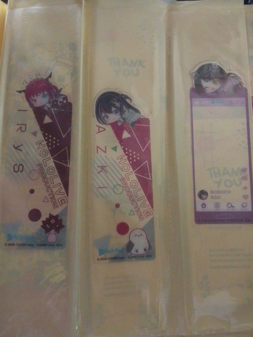 Hololive Production IRyS, AZKi, and Roboco Bookmark (Category: Character Goods) located in Santa Rosa. Submitted by animemerchcollection (Listing ID 1438151010, Image 1). Description: - Hololive Production bookmark set featuring IRyS, AZKi, and Roboco. - Set includes three bookmarks. - Each bookmark has a unique design. - Comes in a clear plastic sleeve. - Roboco bookmark: Social media-style design. - Other bookmarks: Triangle design..