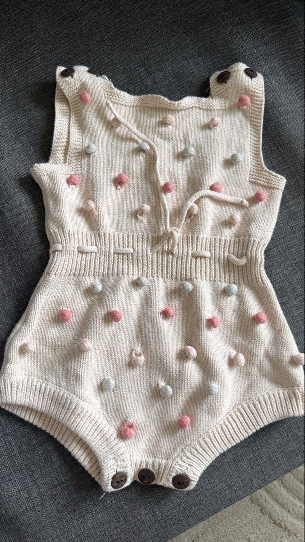 Knitted Baby Romper with Pom Poms (Category: Babies & Kids Fashion) located in Mandaluyong City. Submitted by girlboss01 (Listing ID 1438163021, Image 1). Description: - Adorable cream-colored knitted baby romper - Features decorative pink and light blue pom poms - Sleeveless design - Convenient button closures at the bottom - Charming tie detail at the chest - Ribbed waist and leg openings - Perfect for your little one!.