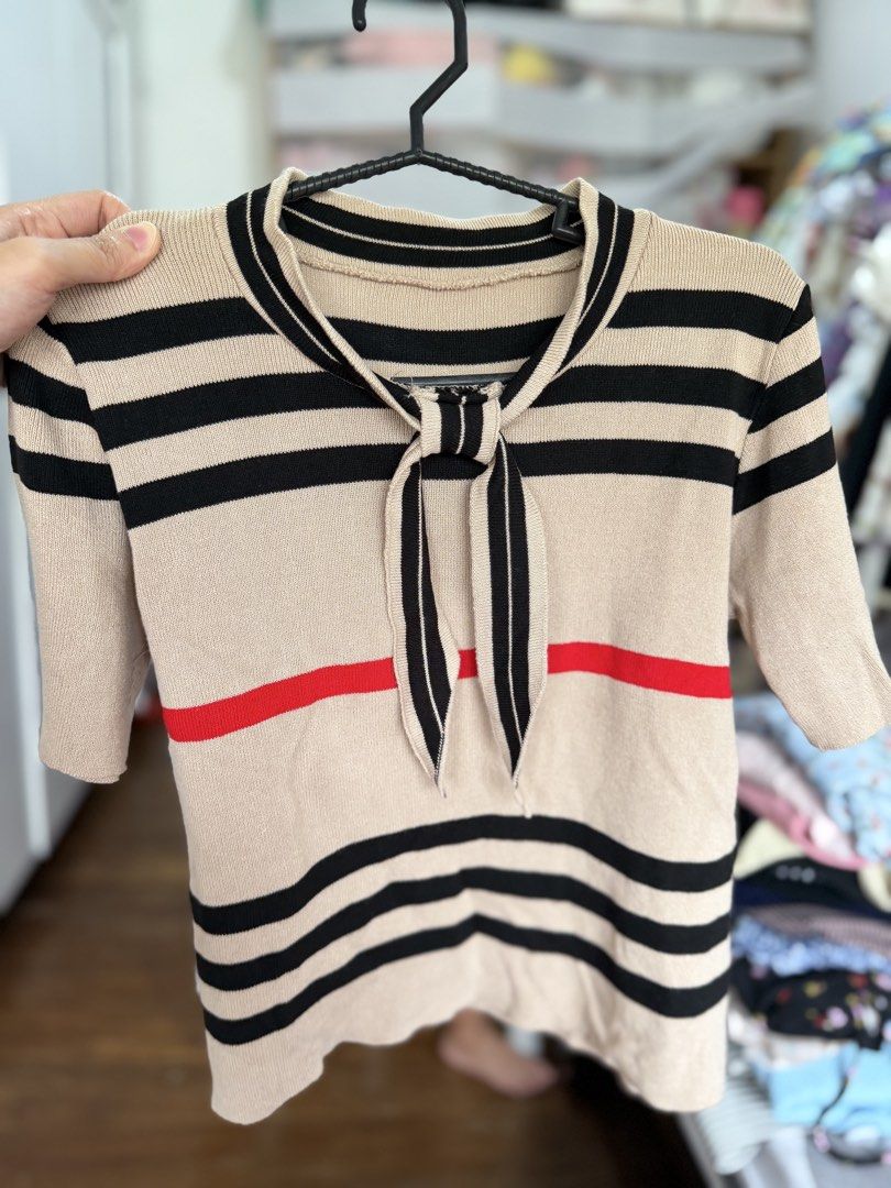 Knitted Striped Soft Knit Top with Tie (Category: Blouses) located in Paranaque City. Submitted by khamsay (Listing ID 1438211719, Image 1). Description: - Beige knit top with black and red stripes - Short sleeves - Tie detail at neckline - Mock neck design - Soft knit material.
