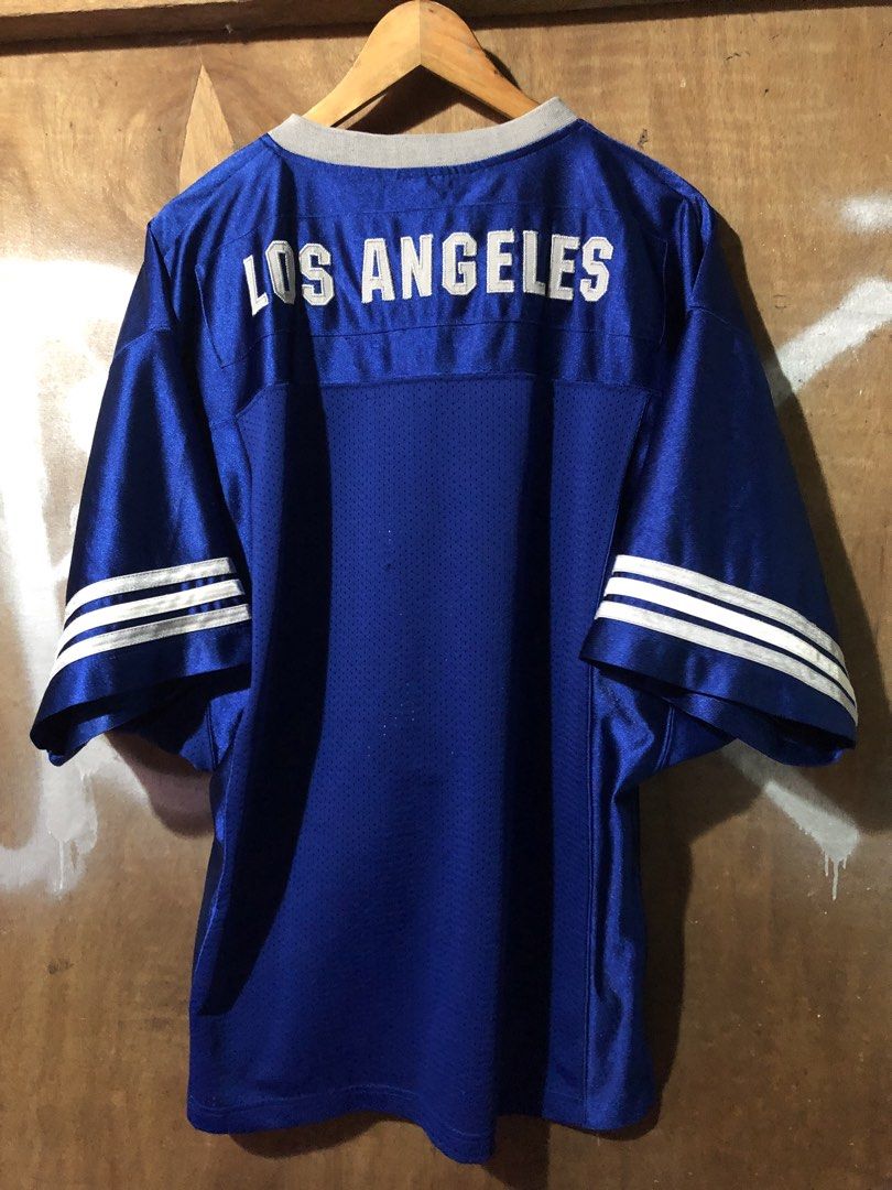 Los Angeles Dodgers Jersey (Category: Activewear) located in Manila. Submitted by bakithrift213 (Listing ID 1438285522, Image 2). Description: - Official Los Angeles Dodgers jersey - Features the team's logo on the front - "LOS ANGELES" printed on the back - Classic blue body with white sleeve stripes - V-neck collar with grey trim - Brand: "Stitches".