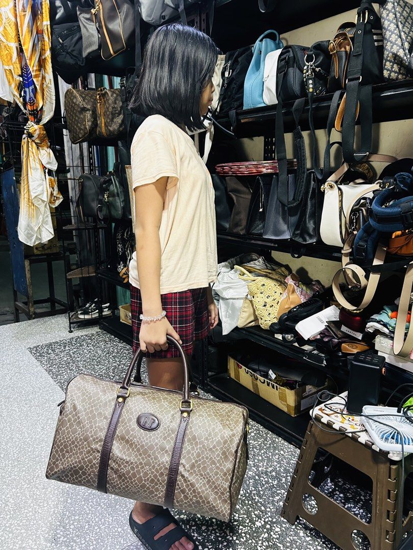 Nina Ricci Travelling Bag (Category: Community) located in Manila. Submitted by starbalesukandjapansurplus (Listing ID 1438277502, Image 3). Description: - Authentic Nina Ricci travel bag - Stylish brown patterned design - Secure top zipper closure - Comfortable dual handles - Elegant brown leather trim - Durable gold-tone hardware - Generous capacity for travel essentials - Features the iconic Nino Cerruti logo.