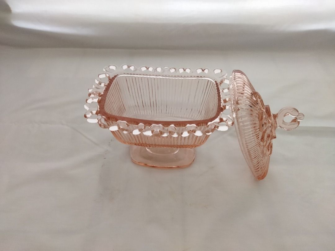 Pink Glass Candy Dish with Lid (Category: Other Kitchenware & Tableware) located in Paranaque City. Submitted by 8prelovedthings8 (Listing ID 1438213333, Image 2). Description: - Pink glass candy dish with matching lid - Square shape with pedestal base - Decorative beaded edge - Lid features a heart-shaped handle - Perfect for candies and small treats - Adds a touch of elegance to any space Measurements: 7" height (with cover) 7" length 5.25" wid