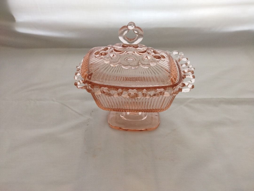 Pink Glass Candy Dish with Lid (Category: Other Kitchenware & Tableware) located in Paranaque City. Submitted by 8prelovedthings8 (Listing ID 1438213333, Image 1). Description: - Pink glass candy dish with matching lid - Square shape with pedestal base - Decorative beaded edge - Lid features a heart-shaped handle - Perfect for candies and small treats - Adds a touch of elegance to any space Measurements: 7" height (with cover) 7" length 5.25" wid