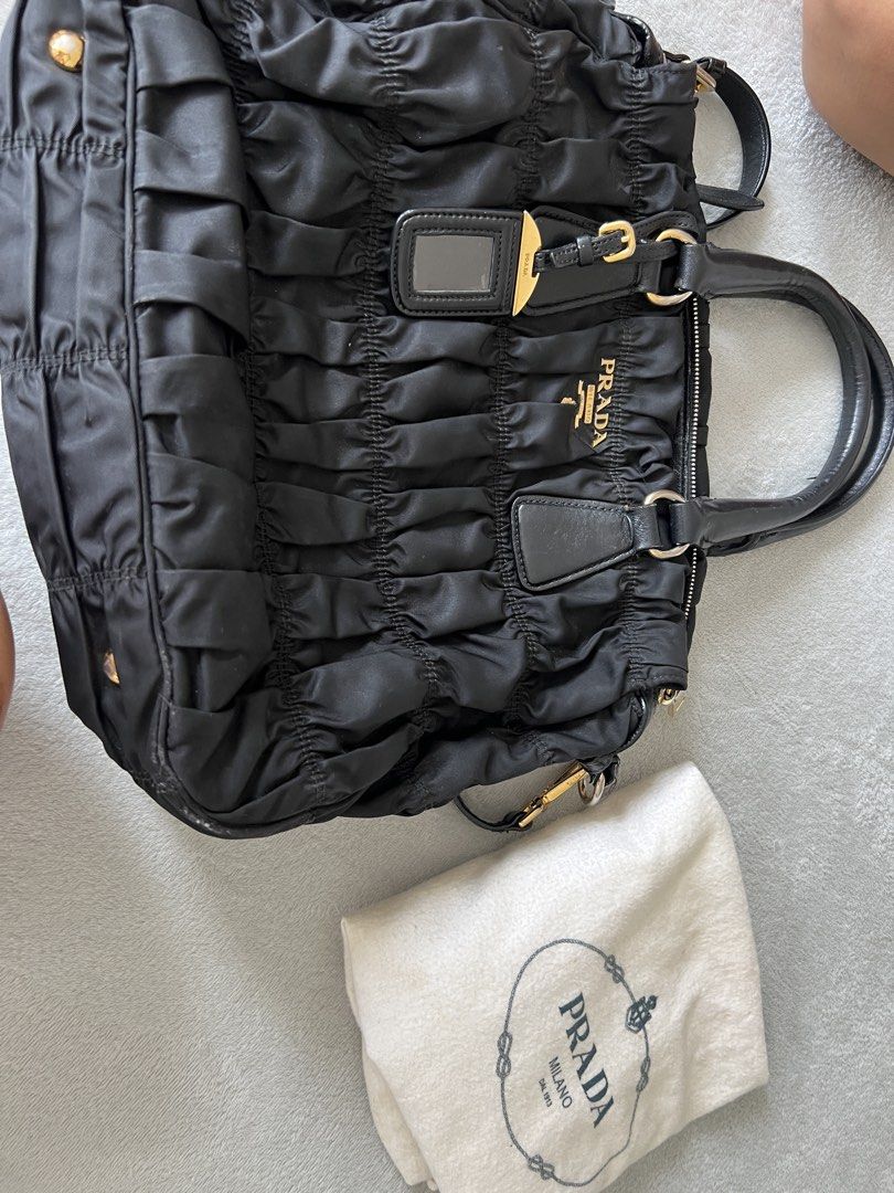 Prada Black Nylon Handbag (Category: Luxury Bags & Wallets) located in Manila. Submitted by eliiiiiiii (Listing ID 1438165465, Image 3). Description: - Authentic Prada handbag - Black nylon material - Ruched design - Gold-tone hardware - Detachable shoulder strap - Includes dust bag - Top handle - Zip closure - Prada logo on front - Small tag detail.