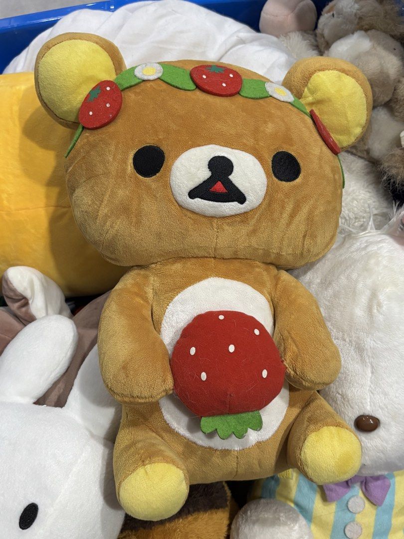 Rilakkuma Strawberry Bear Plush Toy (Category: Plushies & Soft Toys) located in Manila. Submitted by mpt99876 (Listing ID 1438139945, Image 1). Description: Adorable Rilakkuma bear plush toy featuring a strawberry theme. The bear is wearing a strawberry and flower crown and holding a strawberry. The plush has a brown body with yellow accents on the ears and feet. The back of the plush has a stitched design. Includes the original tag..
