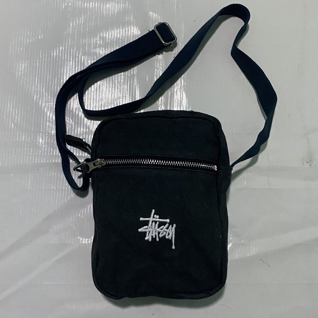 Stussy Crossbody Bag (Category: Sling Bags) located in Manila. Submitted by emjaytricks (Listing ID 1438250441, Image 1). Description: - Black Stussy crossbody bag - Main compartment with zipper closure - Adjustable strap for a comfortable fit - Features the iconic Stussy logo embroidered on the front - Includes an interior tag with Stussy branding and product details - Perfect size for carrying your everyday essentials.