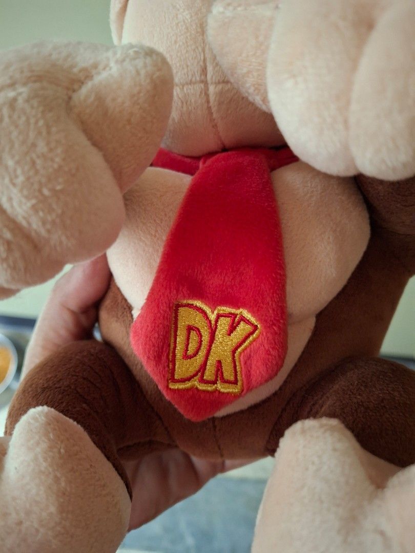 Super Mario Donkey Kong Plush Toy (Category: Plushies & Soft Toys) located in Quezon City. Submitted by pure_trinsky (Listing ID 1438164323, Image 3). Description: - Official Donkey Kong plush toy - Features signature red tie with "DK" logo - Classic brown body, tan face, hands, and feet - Includes original tag - Licensed Super Mario product.
