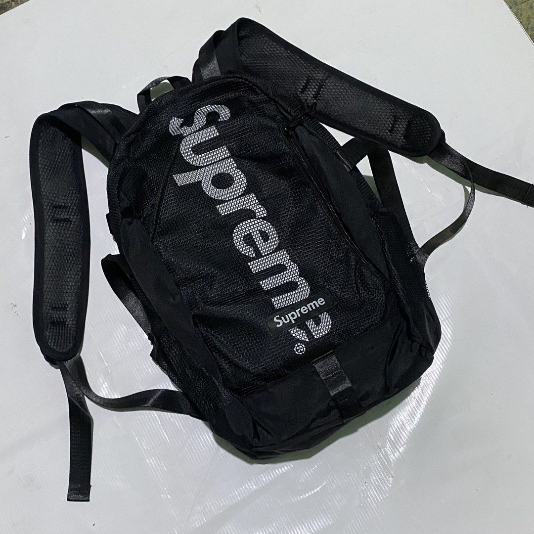 Supreme Backpack Black (Category: Backpacks) located in Manila. Submitted by emjaytricks (Listing ID 1438250702, Image 3). Description: Black Supreme backpack with the brand name prominently displayed on the front and back. Features adjustable straps, multiple compartments, and side pockets. Includes a top handle for easy carrying. The backpack has a mesh design on the front and back for breathability. Supreme logo is also visible on the bottom f