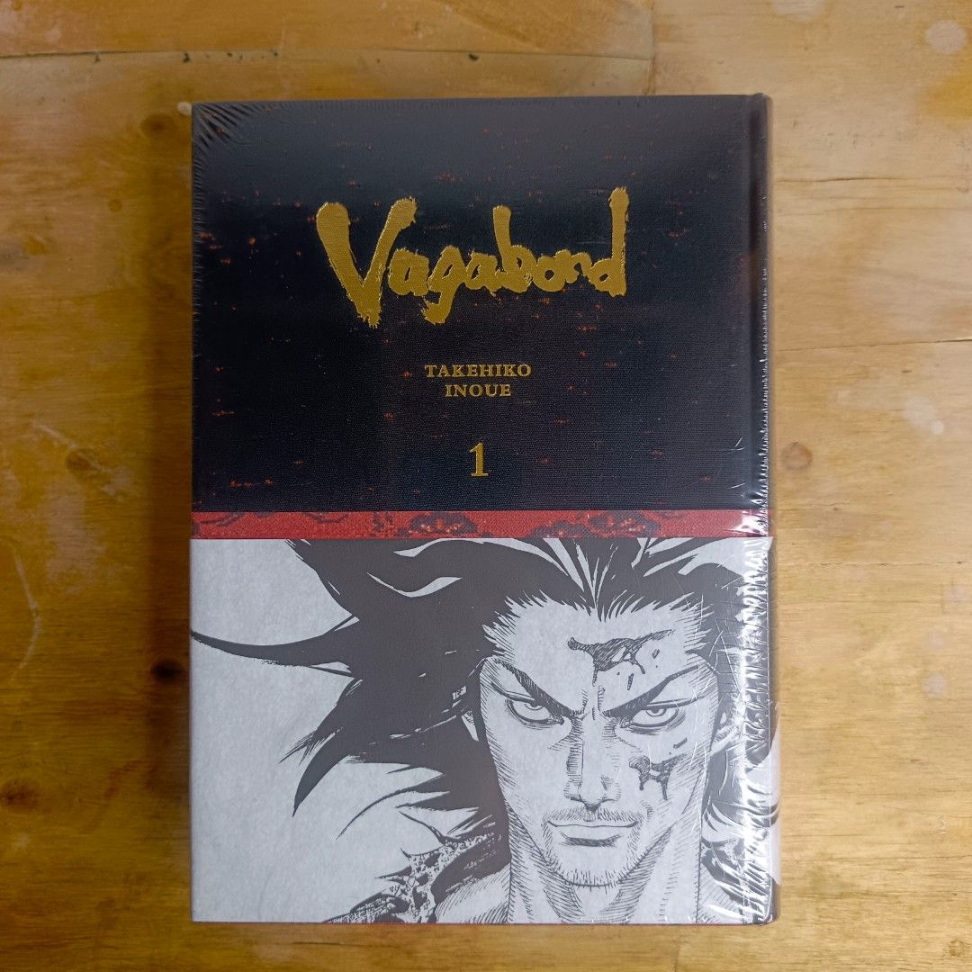 Vagabond Definitive Edition Vol. 1 (Category: Comics & Manga) located in Manila. Submitted by shelfenjoyment (Listing ID 1438297448, Image 1). Description: Vagabond Definitive Edition Vol. 1 by Takehiko Inoue. This edition is still sealed in its original packaging. The book features a striking cover design with gold lettering and a detailed illustration. The spine also displays the title, author, and volume number. A red ribbon is included as a b