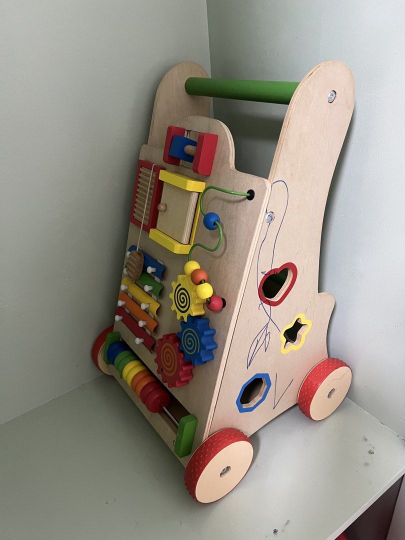 Wooden Montessori Interactive Baby Push Walker (Category: Infant Playtime) located in Cainta. Submitted by ttrreeeesshh (Listing ID 1438287973, Image 1). Description: - Brand: Hoshi - Original Price: Php1,950 - RFS: Decluttering - Wooden push walker - Includes gears, abacus, xylophone, and bead maze - Sturdy handle for easy pushing - Light-colored wood frame - Red wheels.