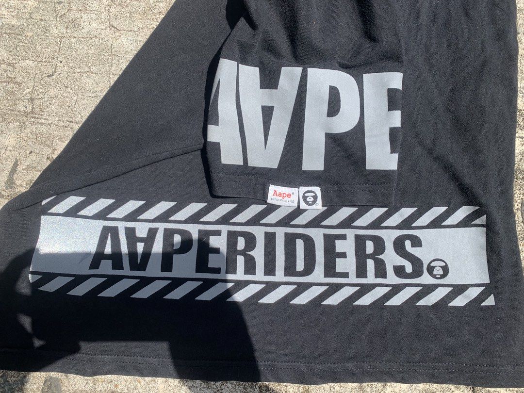 Aape by A Bathing Ape Hyperiders T-shirt (Category: Tshirts & Polo Shirts ) located in Davao. Submitted by lelouchfinds (Listing ID 1438421526, Image 3). Description: - Aape by A Bathing Ape T-shirt in black. - Features a large Ape Head graphic on the front. - "AVPERIDERS" printed on front and back. - "AAPE" printed on sleeves. - Crew neck design. - Size: L. - Reflective design..