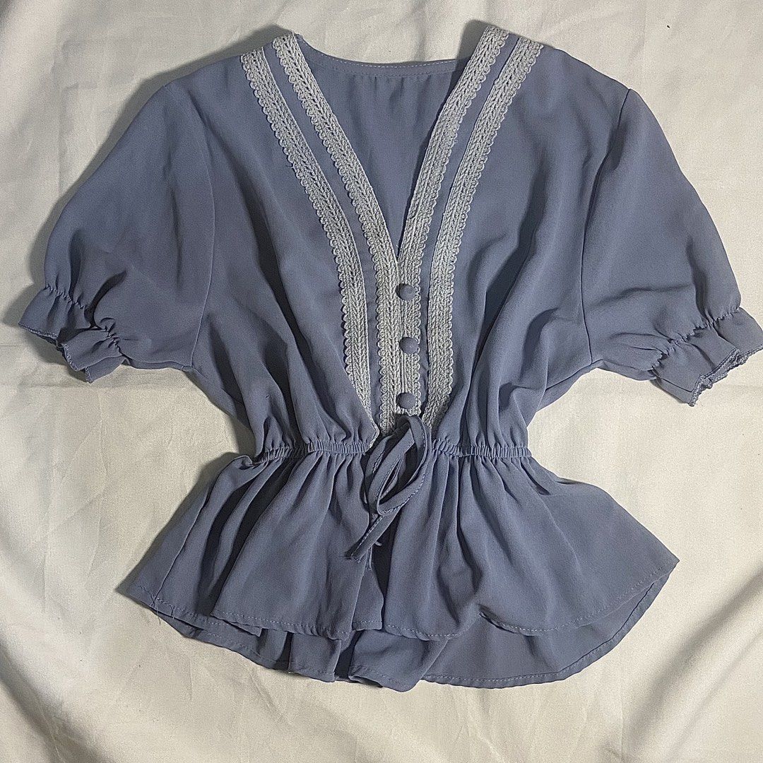 Blue V-Neck Blouse with Lace Trim (Category: Blouses) located in Tarlac. Submitted by glam1x_ (Listing ID 1438458545, Image 1). Description: - Blue V-neck blouse - Delicate lace trim - Short, ruffled sleeves - Cinched waist with drawstring - Three front buttons - Lightweight and flowy fabric.