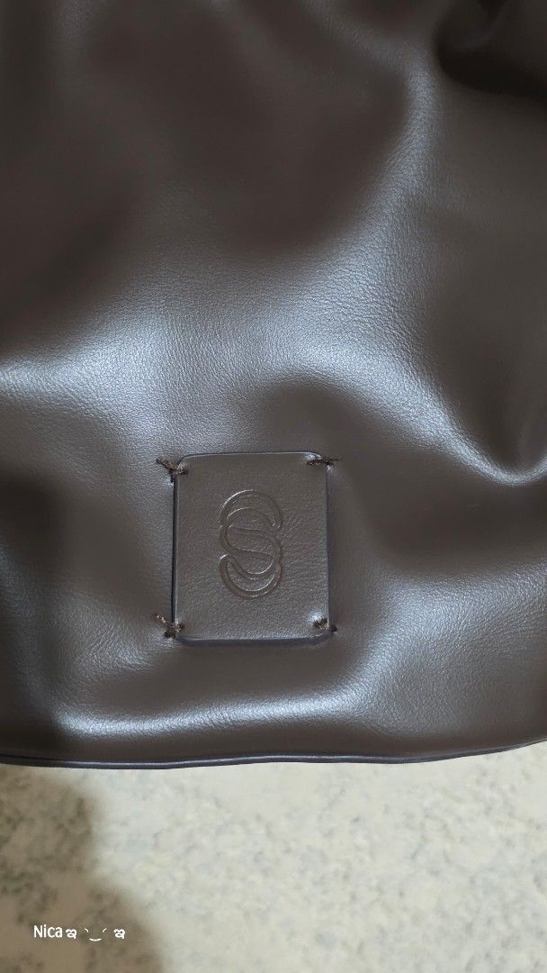Brown Drawstring Handbag (Category: Tote Bags) located in Quezon City. Submitted by prelovedbox2016 (Listing ID 1438344403, Image 2). Description: - Brown drawstring handbag - Includes a shoulder strap - Square logo patch detail - Lined interior - Drawstring closure - Adjustable shoulder strap.